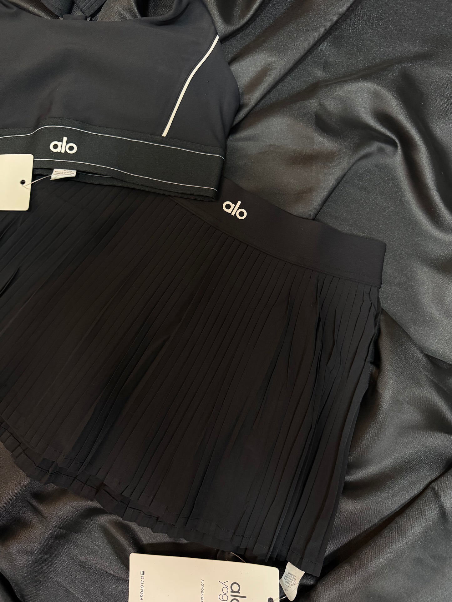 Alo Yoga – Conjunto Bra & Falda Plisada Negra con Detalles en Blanco