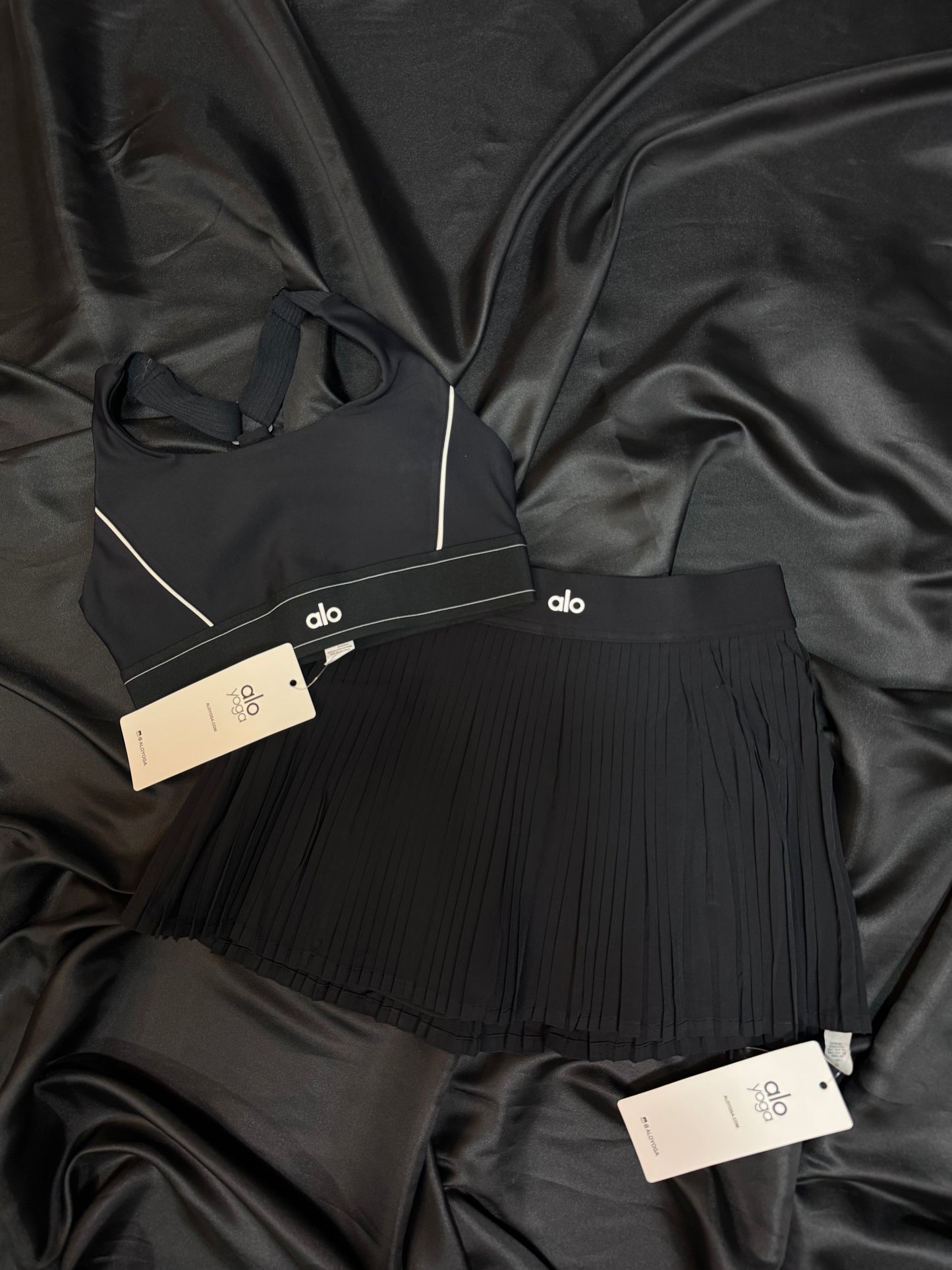Alo Yoga – Conjunto Bra & Falda Plisada Negra con Detalles en Blanco